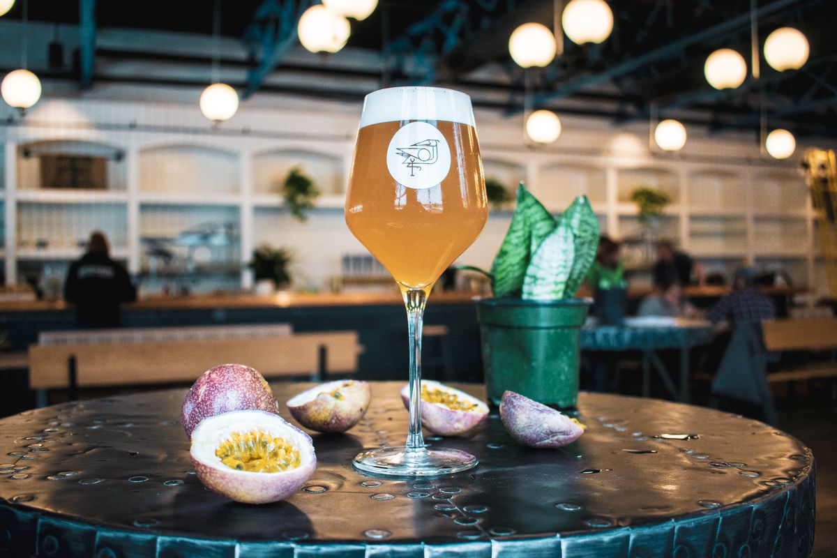 A tulip glass filled with beer and surrounded by sliced passionfruit.