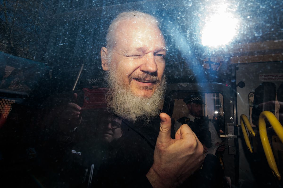 Julian Assange gestures to the media from a police vehicle on his arrival at Westminster Magistrates court on April 11, 2019 in London, England.