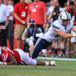 BYU quarterback Tanner Mangum (12) leaps for extra yards after being tripped by Nebraska defensive end Greg McMullen (90) during the second half of an NCAA college football game in Lincoln, Neb., Saturday, Sept. 5, 2015. BYU won 33-28. (AP Photo/Nati Harnik)