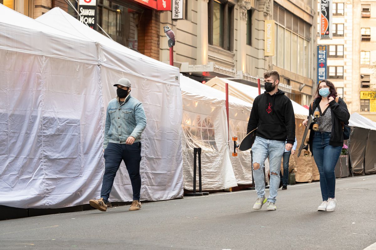 People walk by outdoor dining tents built in Korea Town as the city continues the re-opening efforts following restrictions imposed to slow the spread of coronavirus on October 17, 2020 in New York City.