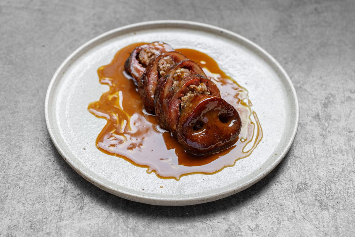 A sliced, stuffed pig snout on a ceramic plate
