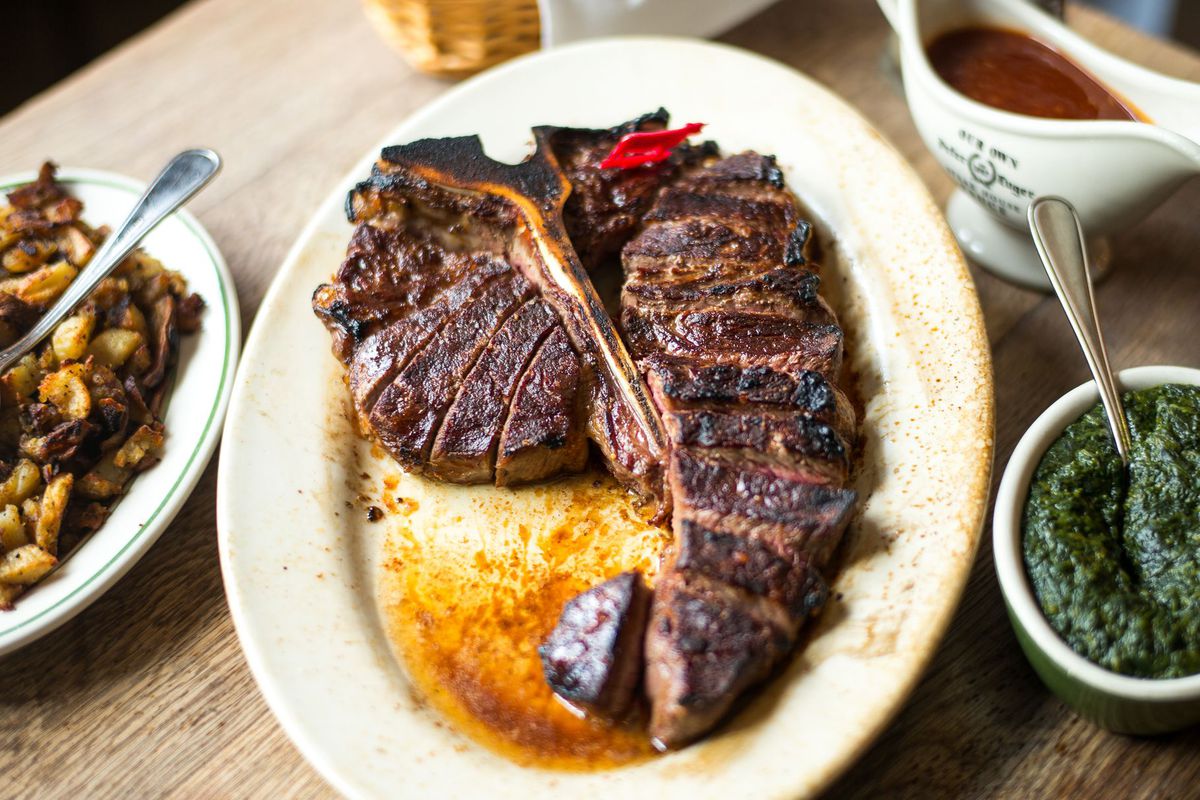 A steak with a massive bone at its center on a plate at Peter Luger in Brooklyn, New York.