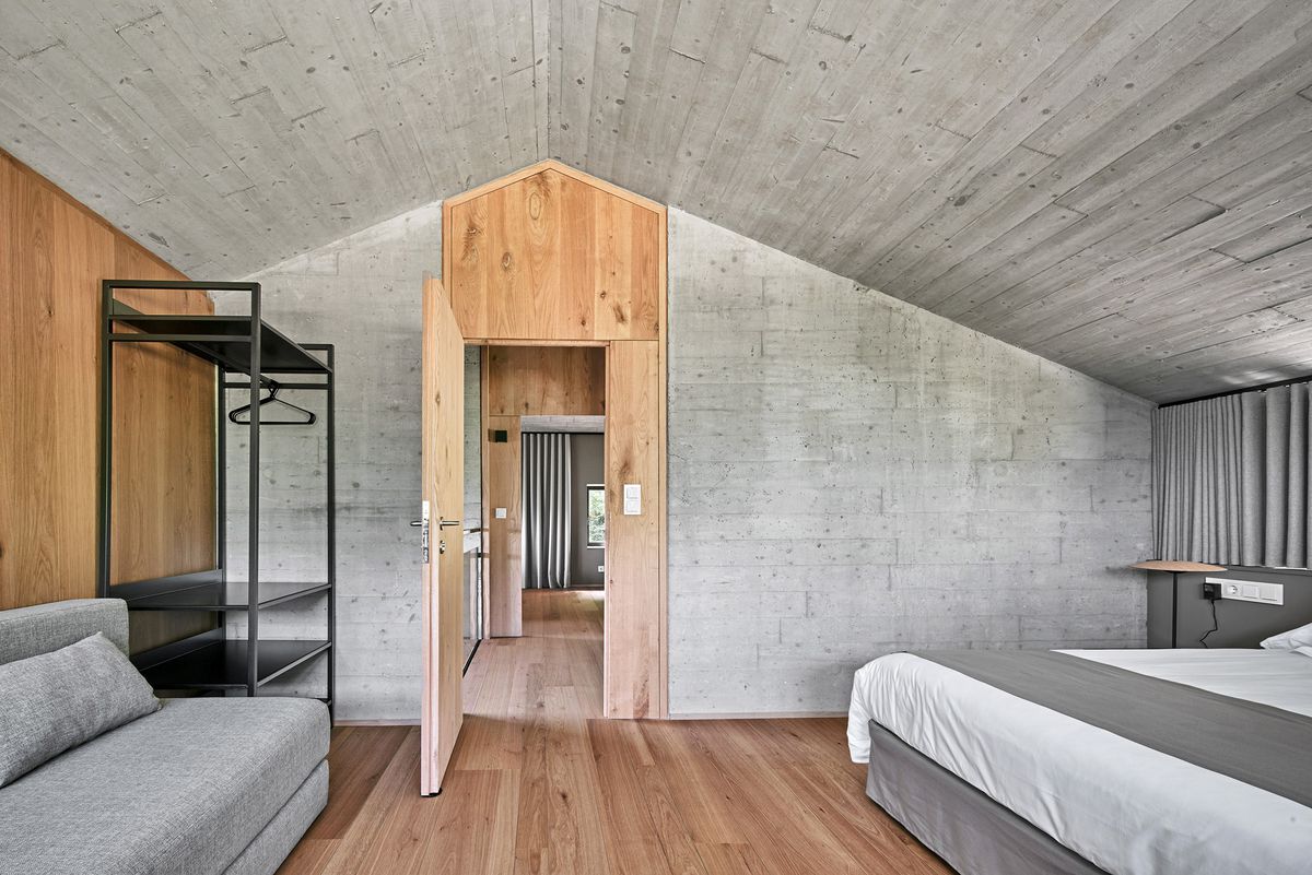 Bedroom clad in wood floors and concrete walls.
