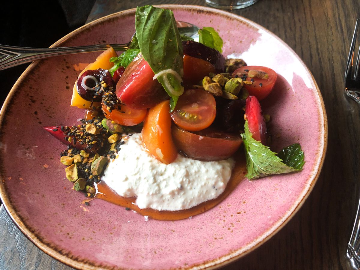 Cut strawberries, cherries, apricots, and nectarines are piled with pistachios and basil over ricotta at Normandie in Portland, Oregon.