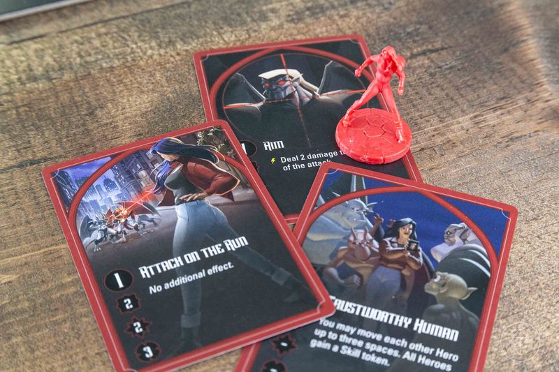 A red character with a collection of her cards, showing her taking aim and shooting a gun.