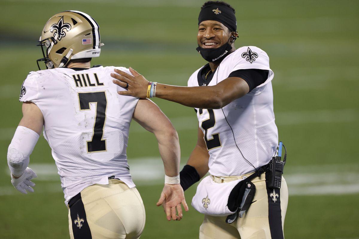 Quarterback Jameis Winston #2 of the New Orleans Saints shares a smile as he greets teammate quarterback Taysom Hill #7 during the second half of their game against the Carolina Panthers at Bank of America Stadium on January 03, 2021 in Charlotte, North Carolina.