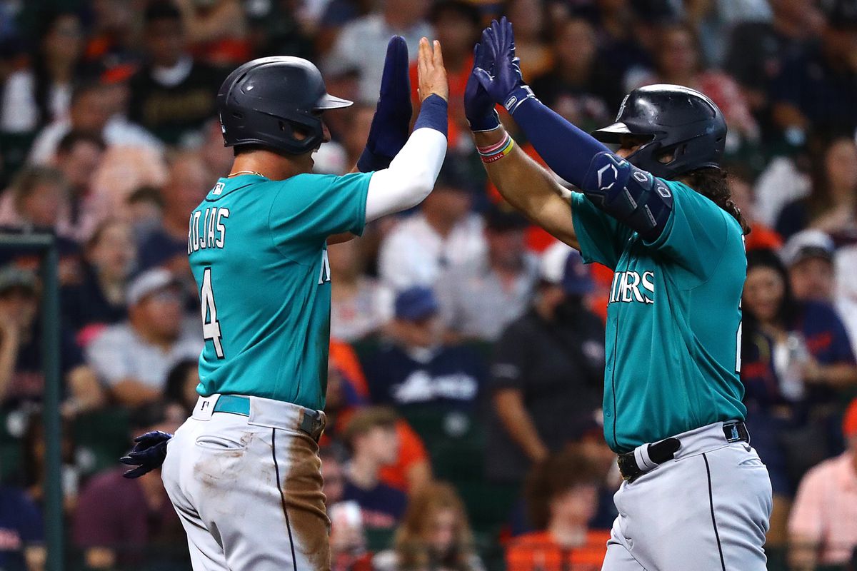 Eugenio Suarez of the Seattle Mariners high-fives Josh Rojas after hitting a two-run home run in the second inning against the Houston Astros at Minute Maid Park on August 20, 2023 in Houston, Texas.
