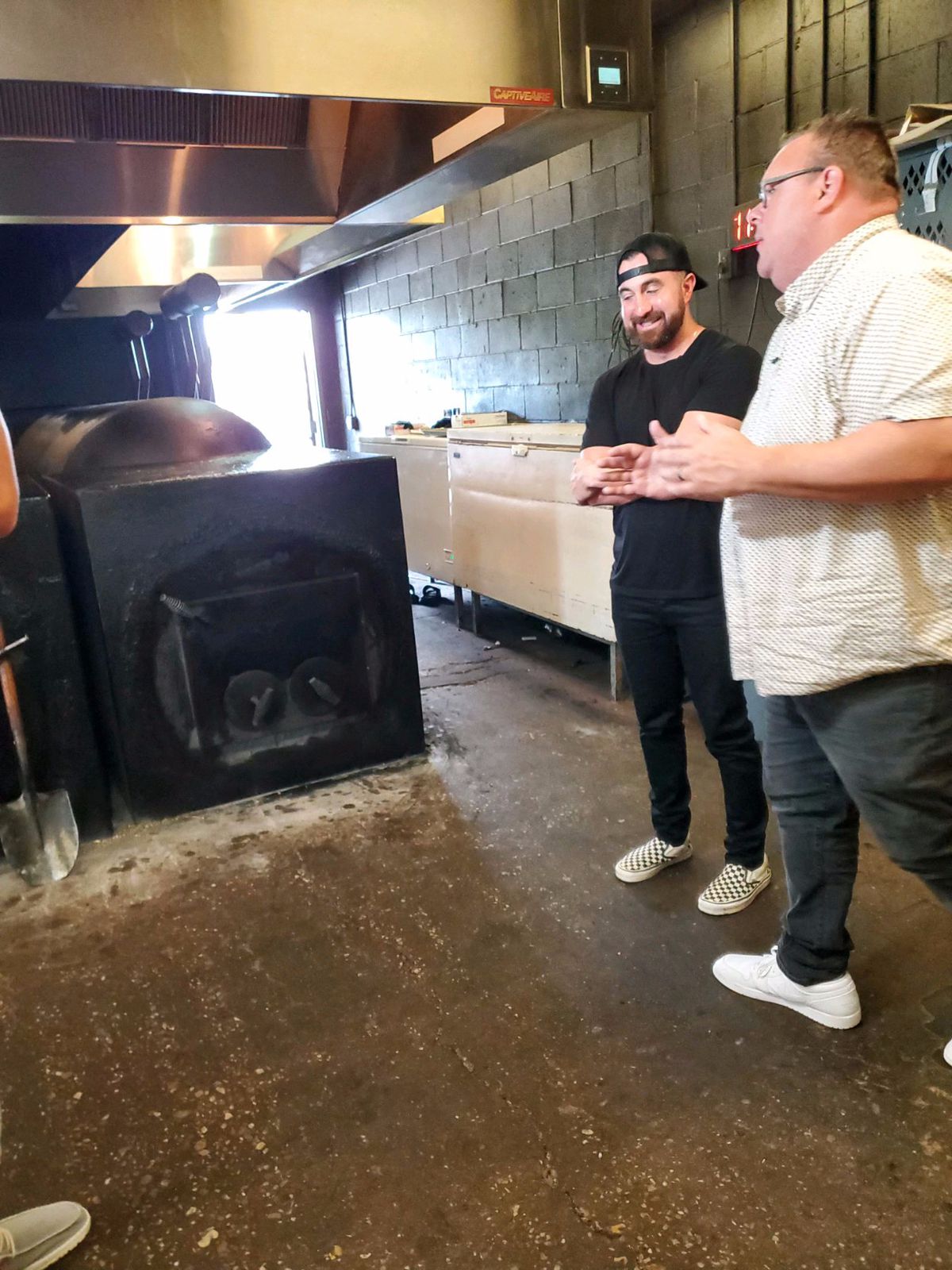 Truth BBQ’s Leonard Botello IV and Chris Shepherd chat inside of a building with barbecue pits.