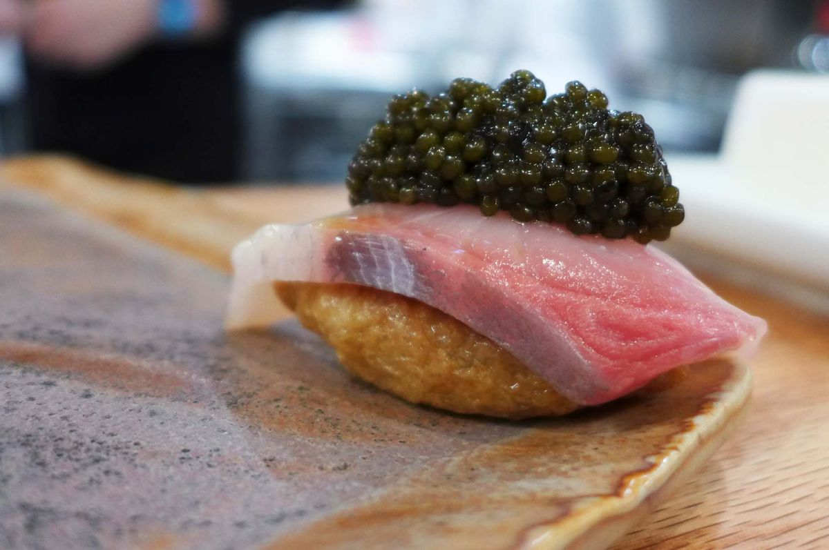 A pink piece of fish with mound of black caviar on top.