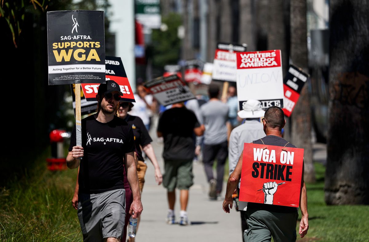 A picket line with union members carrying signs that read “WGA on strike” and “SAG-AFTRA supports WGA.”