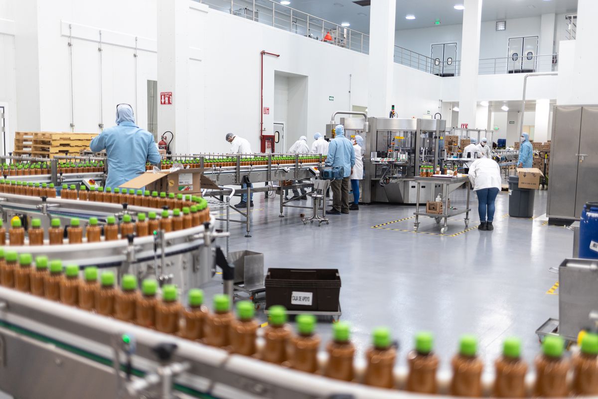 Tajín’s factory in Houston, with employees tending bottles of Tajín on a conveyor belt.