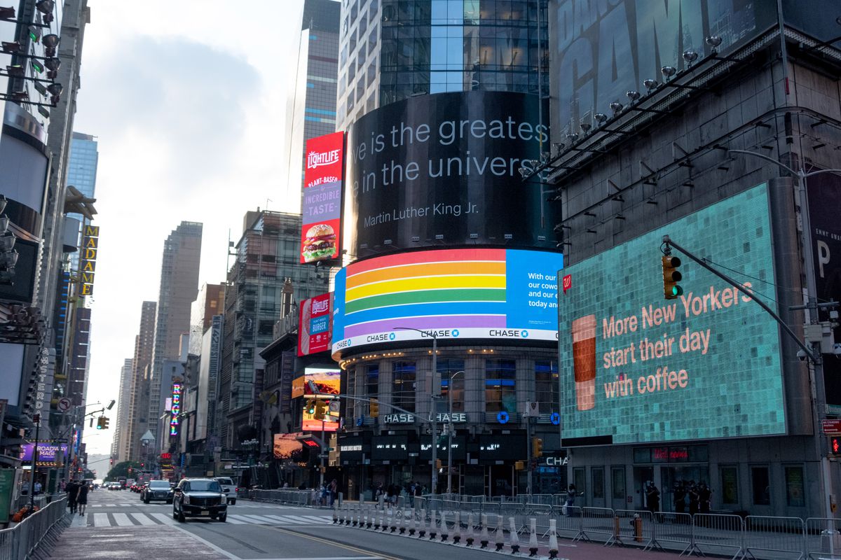 The curved video screen over the entrance to a Chase Bank building in New York City displays a rainbow flag for Pride month.