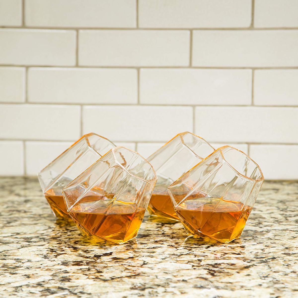 Four diamond whiskey glasses filled partway with whiskey