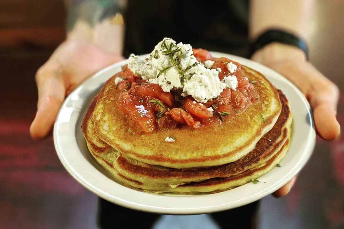 A pair of hands holds a plate of savory pancakes.