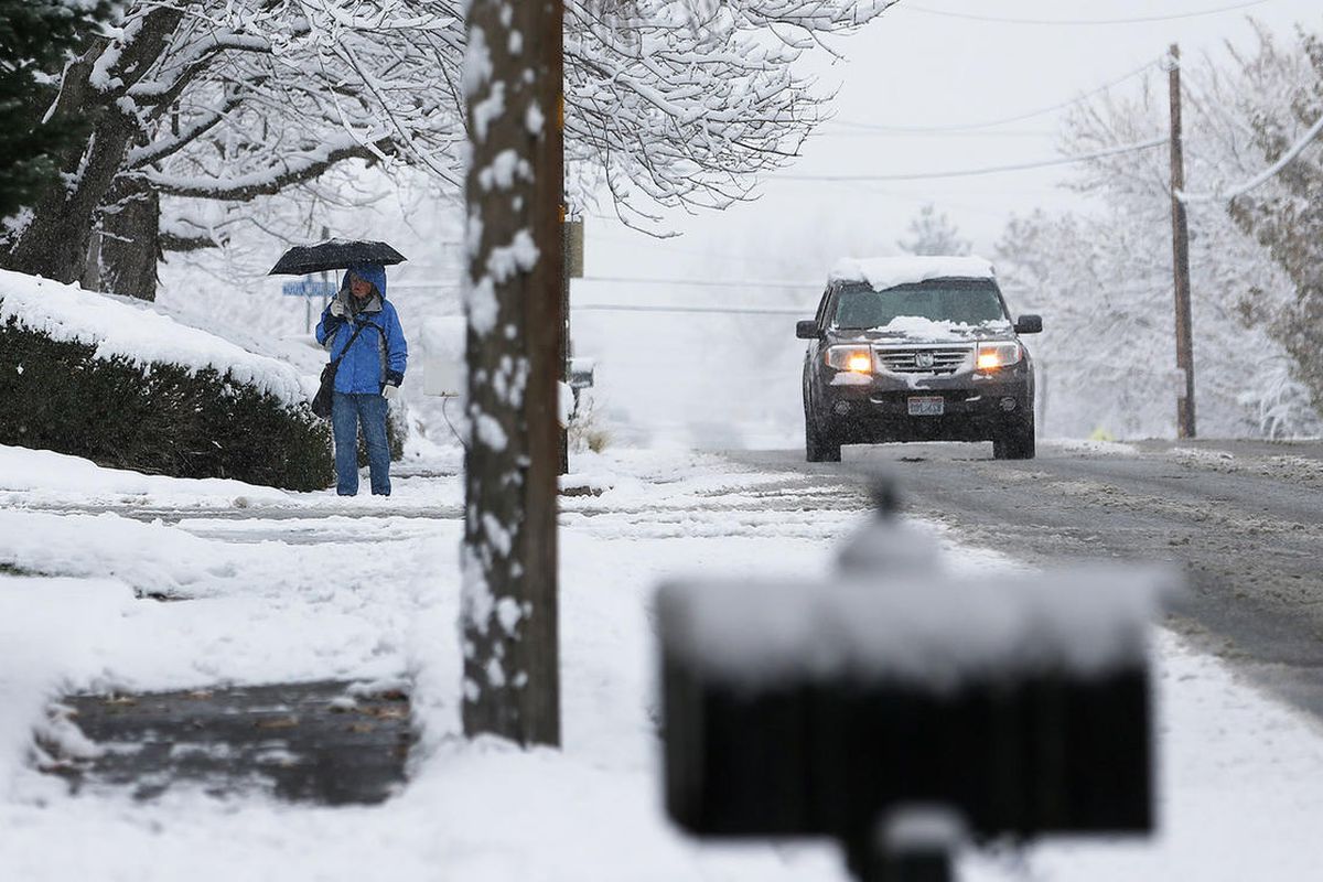 FILE - A woman walks with an umbrella as a car passes in Centerville as Wasatch front residents deal with a winter storm On Monday, Nov. 28, 2016. An avalanche warning has been issued and hundreds of homes lost electricity as brisk winds whipped through n