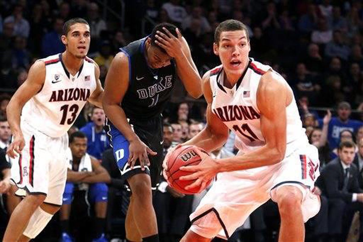 Arizona's Aaron Gordon (11) looks to pass after securing possession away from Duke's Jabari Parker (1) after Arizona's Nick Johnson (13) blocked Parker's shot during the second half of an NCAA college basketball game in the championship of the NIT Season 