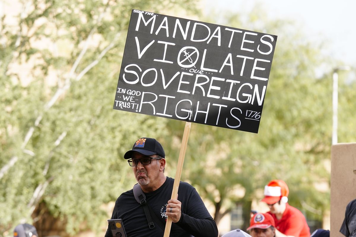 One of many anti-vaccine mandate activists holds a sign during a rally outside Phoenix City Council chambers in early December as the city paused implementation of a federal COVID-19 vaccine mandate for 14,000 city workers.