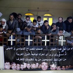 A man mourns over Egyptian Coptic Christians who were captured in Libya and killed by militants affiliated with the Islamic State group, inside the Virgin Mary Church in the village of el-Aour, near Minya, 220 kilometers (135 miles) south of Cairo, Egypt, Monday, Feb. 16, 2015. Egyptian warplanes struck Islamic State targets in Libya on Monday in swift retribution for the extremists' beheading of a group of Egyptian Christian hostages on a beach, shown in a grisly online video released hours earlier. The banner in Arabic reads, "poor for a piece of bread.. Victims of political and religious conflict, we did not hear nor see any reactions from Arab nations to save the lives of these Christians from the hands of extremists. " 