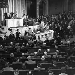 U.S. President Harry S. Truman, standing at podium, addresses a joint session of Congress in the House Chamber in Washington, D.C., March 12, 1947. President Truman urged aid for Greece and Turkey.  
Seated behind the president at left is Sen. Arthur Vandenberg, R-Mich., president pro-tem of the senate, and at right is House Speaker Joseph Martin, R-Massachusetts. Seated center foreground, from left, are, Fleet Adm. William D. Leahy, chief of staff; Maj. Gen. Harry Vaughan; Adm. James Foskett, military and naval aides to the president, respectively.  
