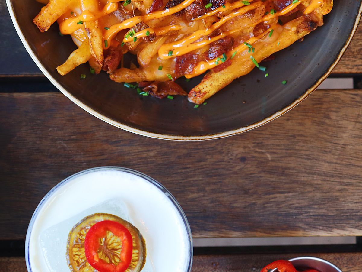A plate of french fries and a side of sauce.