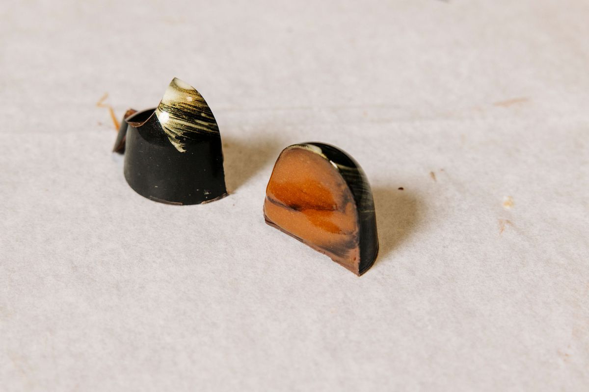 A bonbon sliced in half to reveal a marbled brown-and-black interior.