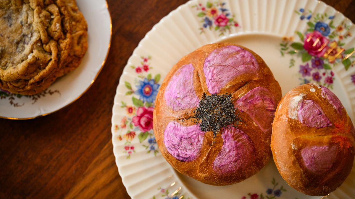 Two Kaiser rolls with pink frosting sit on a floral plate at Flour Bloom.