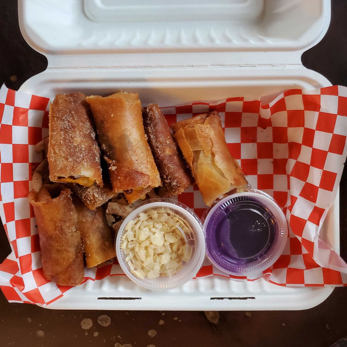 Pieces of banana are wrapped in a fried, crispy lumpia wrapper with small sauce containers of ube dipping sauce and Rice Krispies cereal.