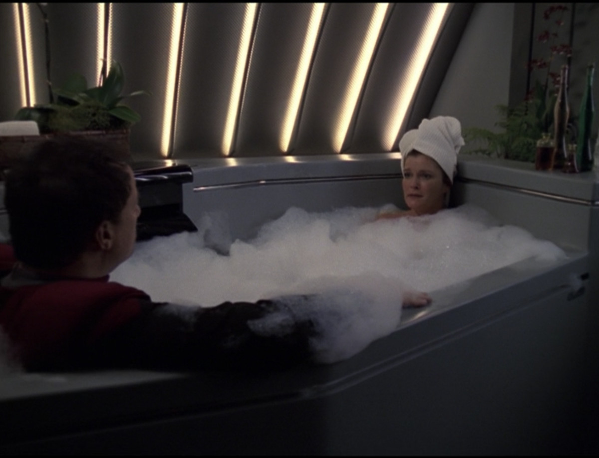 Q sitting (fully clothed) in a bubble bath with Captain Janeaway