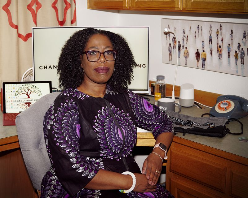 A woman in a print dress sits at her desk.