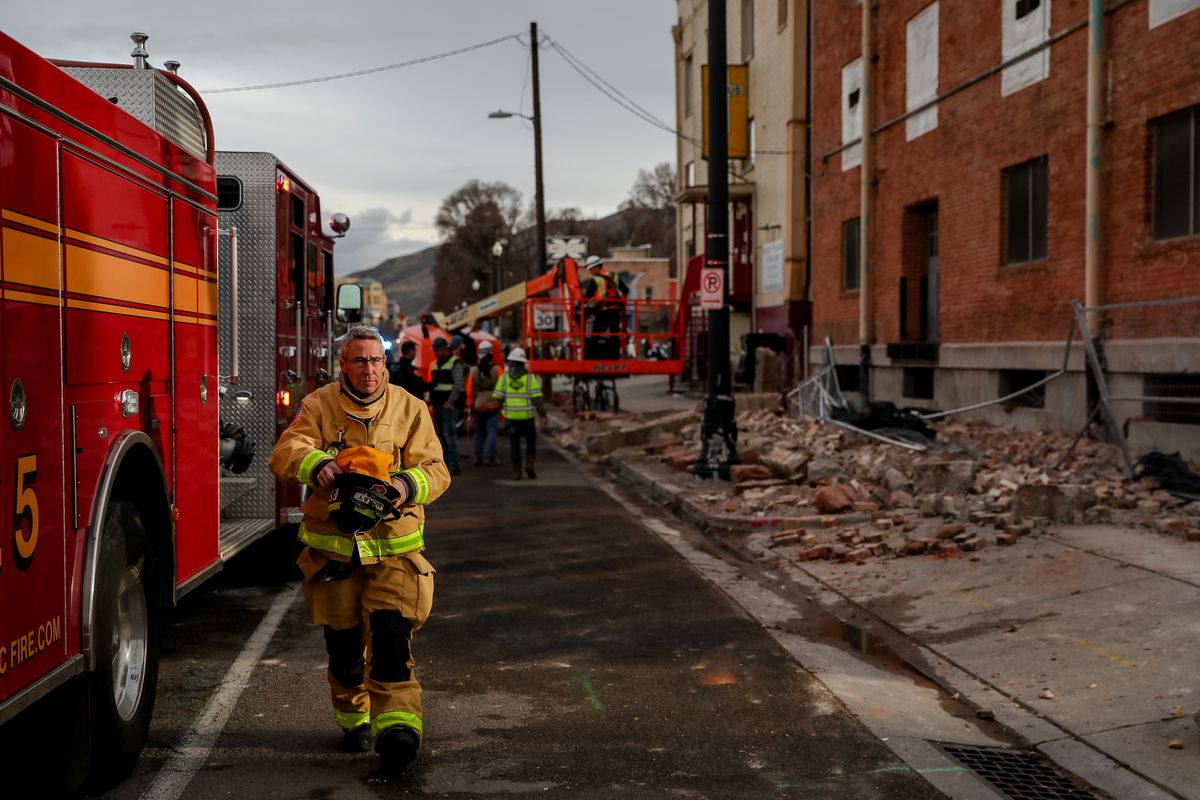 A firefighter arrives on scene where debris fell off a building at 400 South and 500 West in Salt Lake City after a 5.7 magnitude earthquake centered in Magna hit early on Wednesday, March 18, 2020.