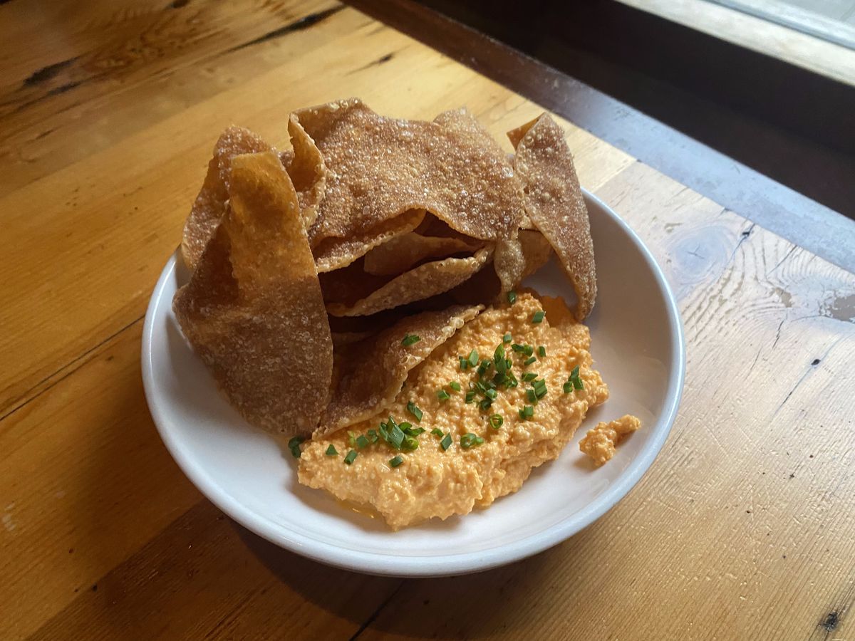 A bowl of fried wontons with kimchi beer cheese basks in the natural light of a nearby window.