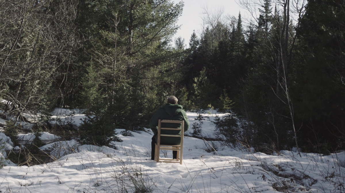 Joe Pera ormanda bir sandalyede oturuyor