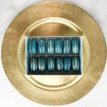 A gold plate holds a box of blue Hanukkah-themed macaroons.