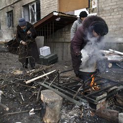 Residents cook outside their damaged apartment building in Debaltseve, Ukraine, Friday, Feb. 20, 2015. After weeks of relentless fighting, the embattled Ukrainian rail hub of Debaltseve fell Wednesday to Russia-backed separatists, who hoisted a flag in triumph over the town. The Ukrainian president confirmed that he had ordered troops to pull out and the rebels reported taking hundreds of soldiers captive. 