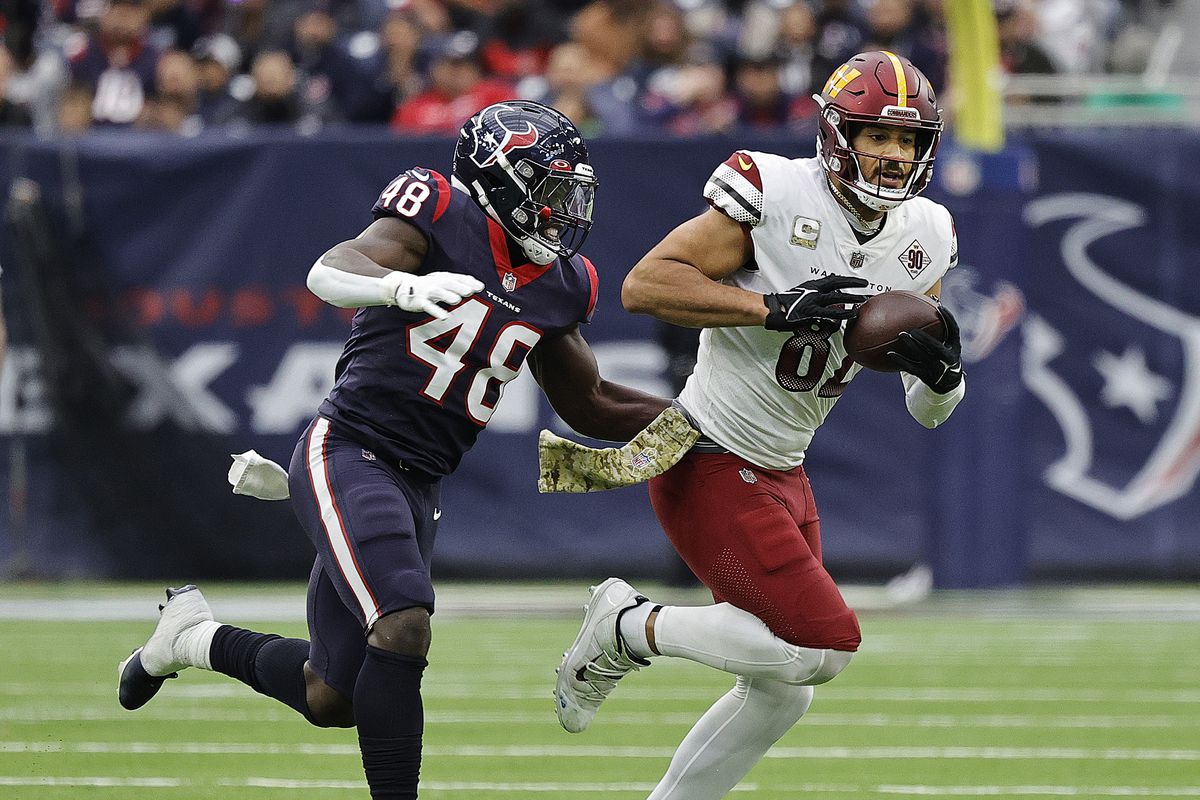 Logan Thomas #82 of the Washington Commanders runs with the ball after a reception as he is pursued by Christian Harris #48 of the Houston Texans at NRG Stadium on November 20, 2022 in Houston, Texas.