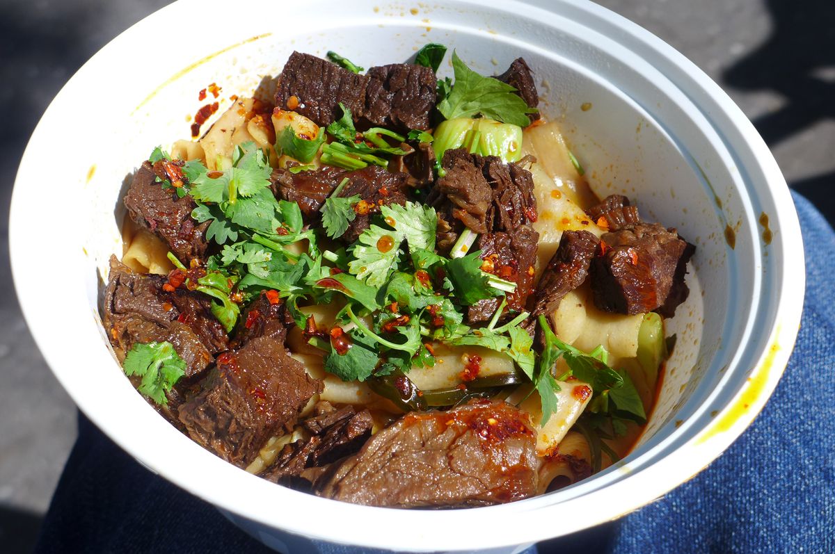A plastic bowl with noodles and brisket.