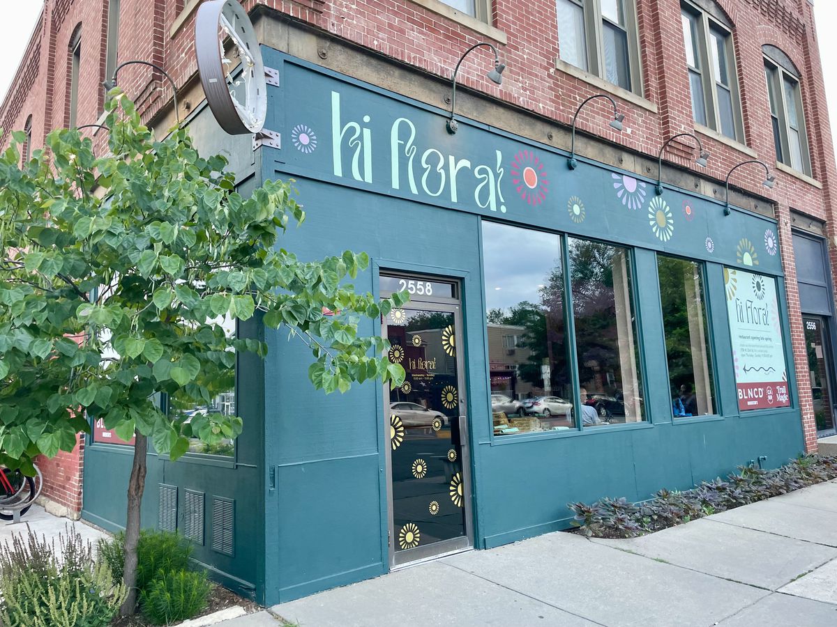 The exterior of a restaurant with a green facade that says “Hi Flora!”