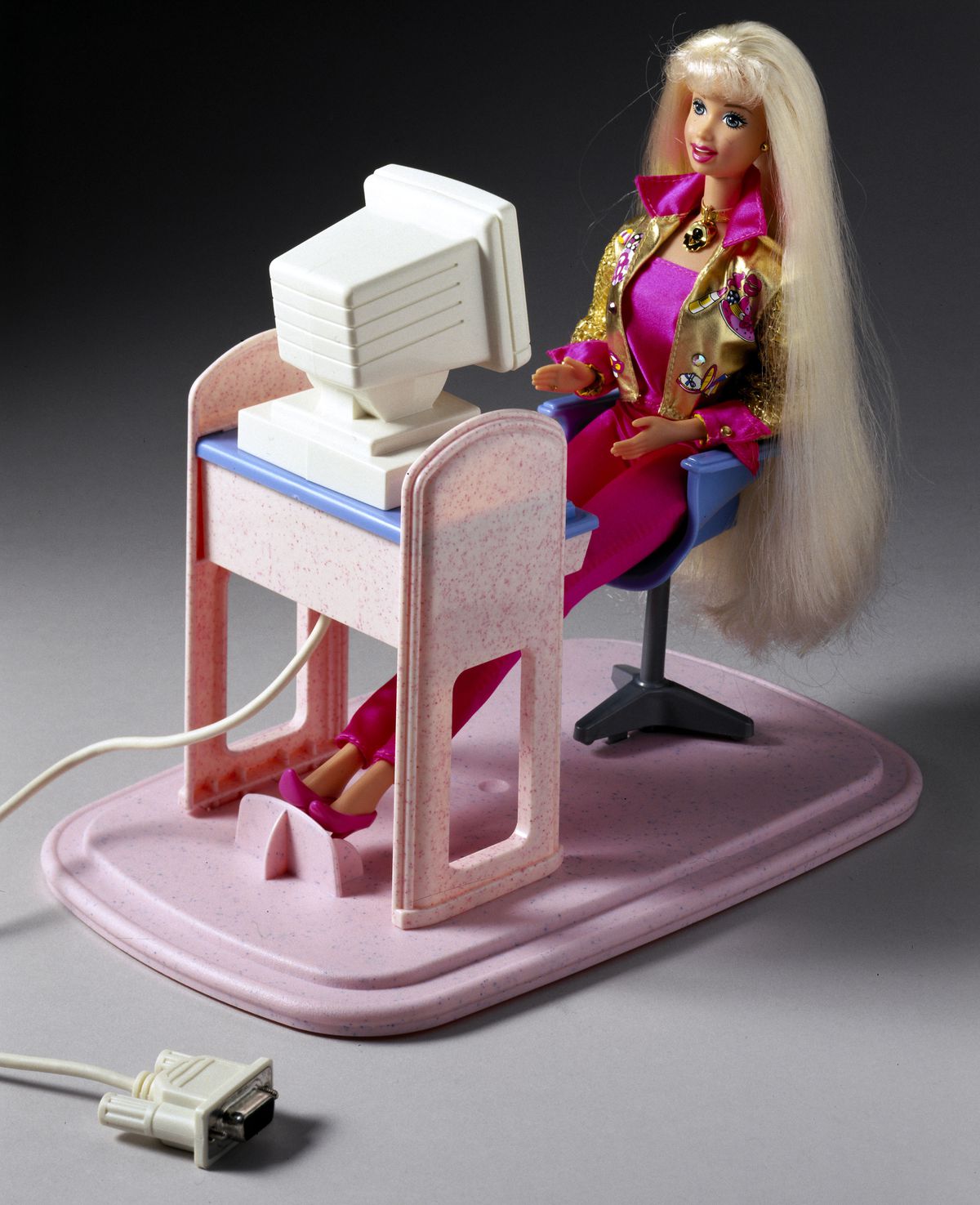 Talk With Me! Barbie doll, USA, 1997, using a computer. There’s a cord sticking out from her machine.