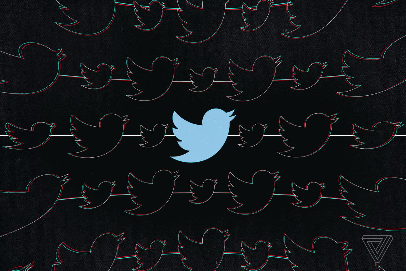 Twitter’s blue bird silhouette logo is seen on a black background.