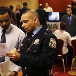 In this Tuesday, Feb. 26, 2013, photo, Philadelphia police recruiting officer Samuel Cruz, right, talks with Ismail Azeer of Carteret, N.J., at the Edison Career Fair job fair in the Iselin section of Woodbridge Township, N.J. The number of Americans seeking U.S. unemployment benefits fell sharply last week to a seasonally adjusted 346,000, suggesting March's weak month of hiring may be a temporary slowdown. Employers added only 88,000 jobs in March after averaging 220,000 the previous four months. The drop in unemployment benefits suggests hiring could pick up again in April. 