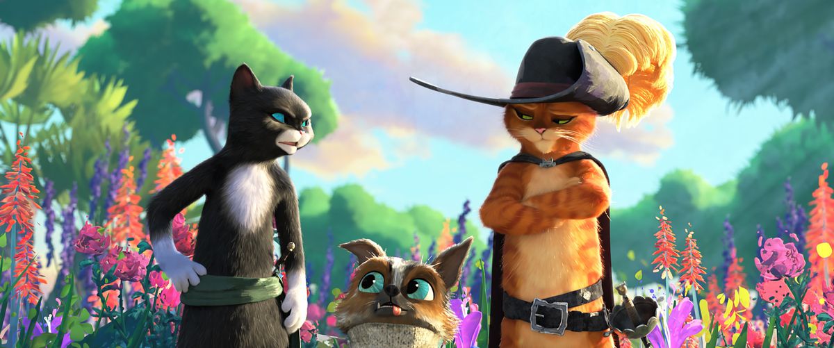 Kitty Softpaws (Salma Hayek), Perro (Harvey Guillén) and Puss stand in a garden filled with watercolor-like flowers and plants