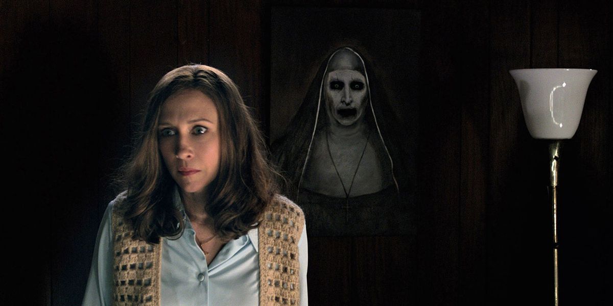 Vera Farmiga dans le rôle de Lorraine Warren se tient devant un portrait de nonne effrayant dans The Conjuring 2