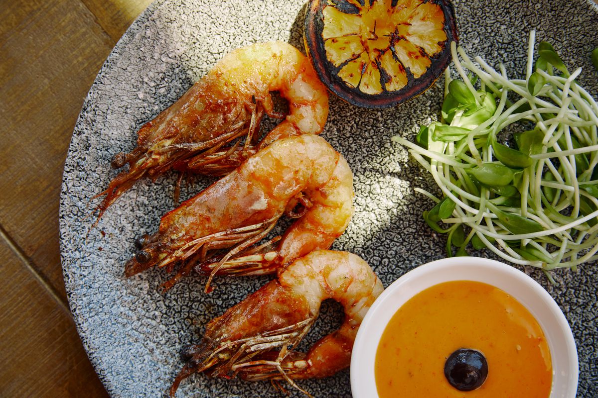 Grilled prawns with lemon, greens, and an aioli dip on a plate at Lemon Grove restaurant in Hollywood, California.
