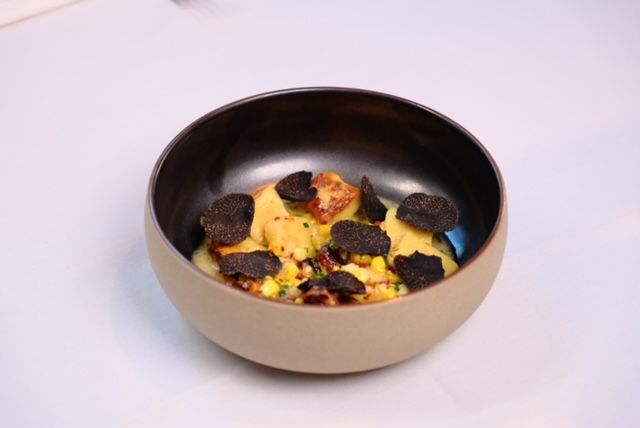 A bowl of gnocchi with corn and truffles. 