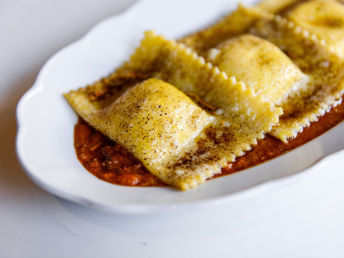 Three plush pieces of stuffed pasta in red sauce.