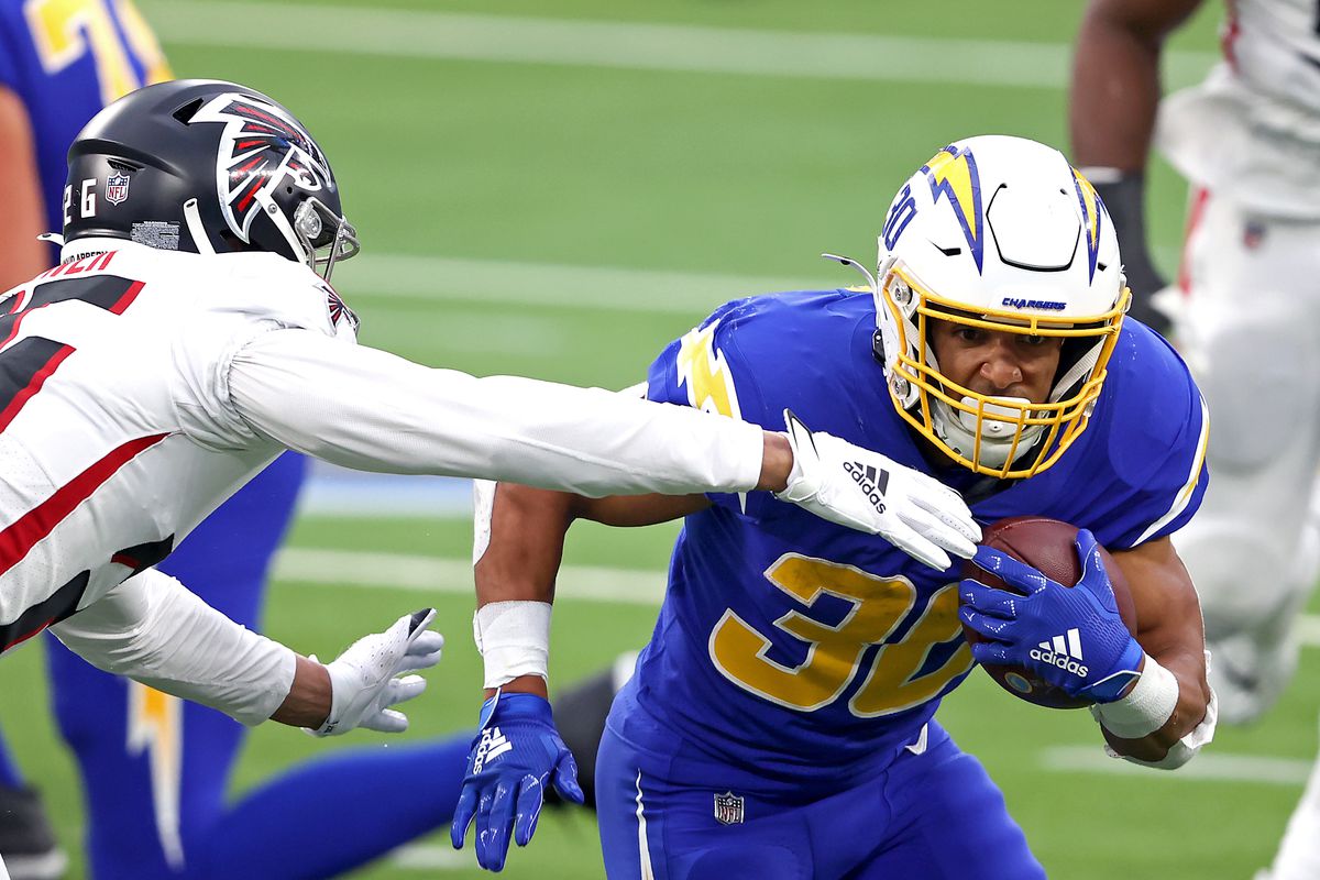 Austin Ekeler #30 of the Los Angeles Chargers runs the ball for a first down against Isaiah Oliver #26 of the Atlanta Falcons during the third quarter at SoFi Stadium on December 13, 2020 in Inglewood, California.