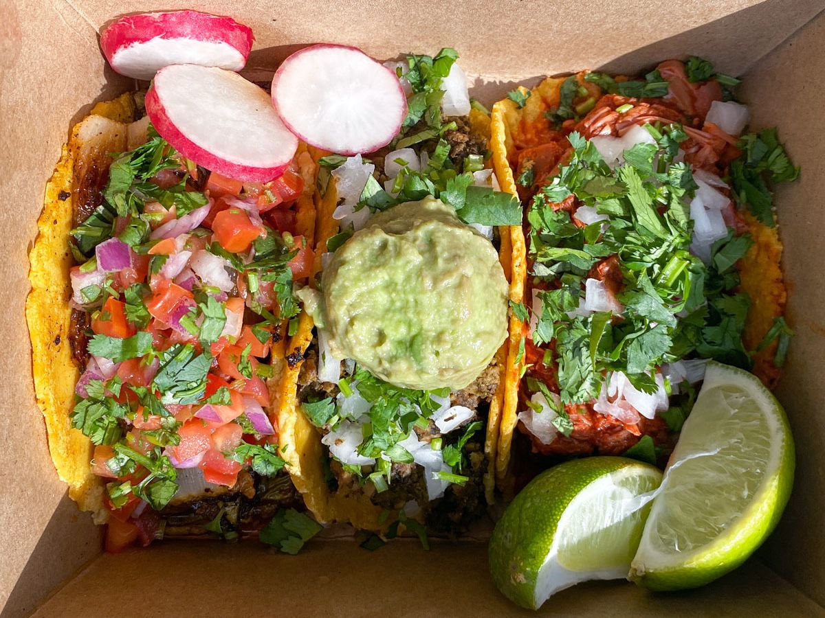 A photo of the nopales, chorizo and potato, and jackfruit birria tacos from La Taquiza Vegana food cart in a takeout box
