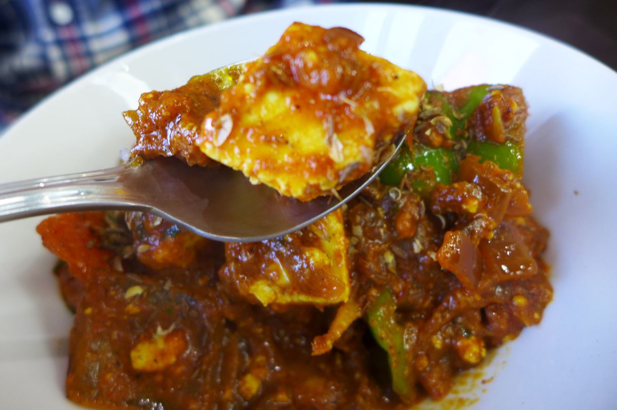 A very red dish jumbled with green peppers and tomatoes but principally containing ragged cubes of paneer cheese...
