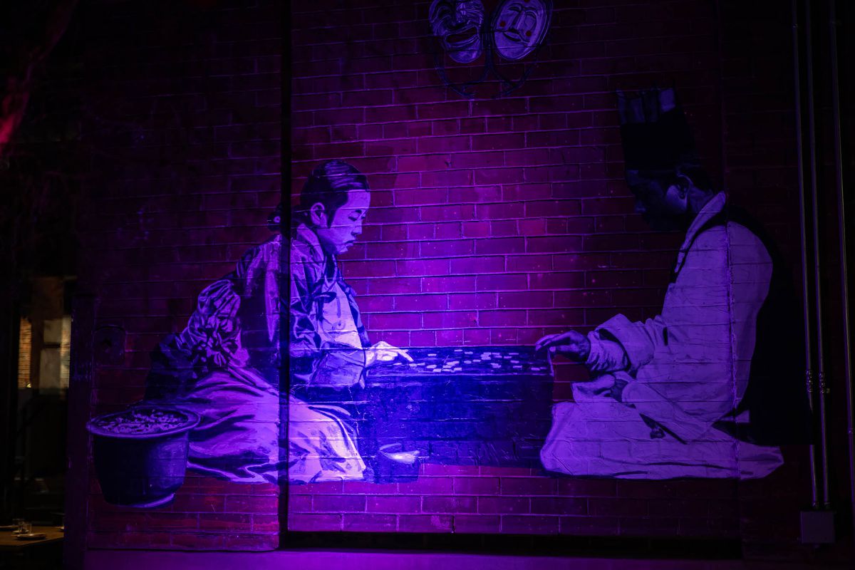 Purple lights show on art of two children playing a boardgame at LA restaurant Yangban.