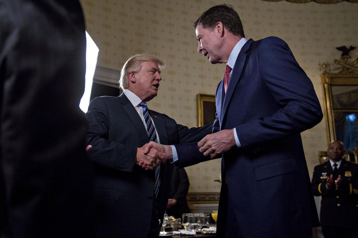 President Donald Trump shakes hands with James Comey, former director of the Federal Bureau of Investigation, during an Inaugural Law Enforcement Officers and First Responders Reception in the Blue Room of the White House on January 22, 2017 in Washington